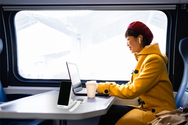 Frau die im Zug sitzt mit dem anco® 3in1 Wireless Charger auf dem Tisch