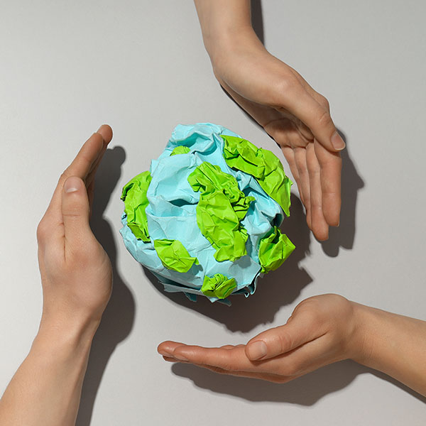 Eco Erdball aus Papier mit schützenden Händen herum